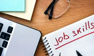 Notatnik z napisem "job skills", laptop i okulary. Przygotowanie do autoprezentacji.