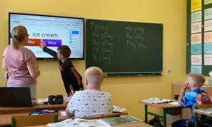 Nauczycielka z dzieckiem przy tablicy interaktywnej, ćwiczą angielski. Ciekawe, ile zarabia nauczyciel klas 1-3 za taką lekcję.