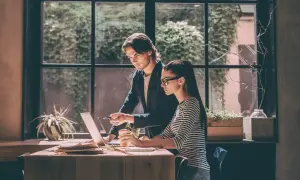 Mężczyzna wskazuje na ekran laptopa, omawiając z kobietą zadania. To dobra opinia o praktykancie, który szybko się uczy.