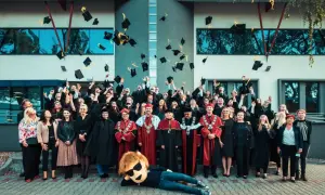 Absolwenci w togach rzucają czapki do góry, świętując zakończenie studiów dualnych. Radosna atmosfera i symboliczne pożegnanie z uczelnią.