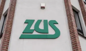 Zielone logo ZUS na jasnej ścianie budynku z ceglanymi elementami.