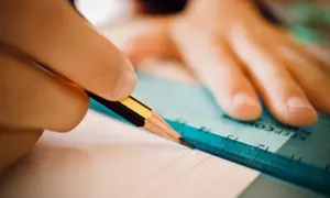 Dłoń z ołówkiem i linijką tworzy zindywidualizowana ścieżka kształcenia, rysując precyzyjne linie na papierze.