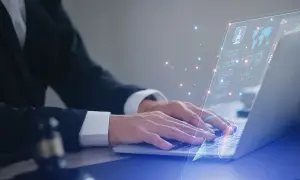 Prawnik w garniturze pracuje na laptopie, na ekranie wyświetla się interfejs z danymi i wykresami, symbolizującymi jego kluczowe kompetencje w cyfrowym świecie.