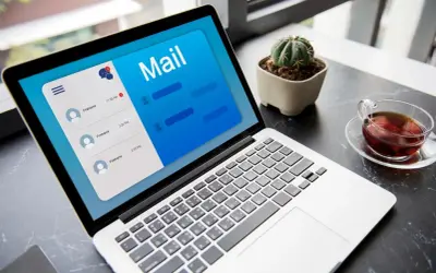 Laptop z otwartą aplikacją poczty, pokazującą jak napisać maila z CV. Obok filiżanka herbaty i mały kaktus.