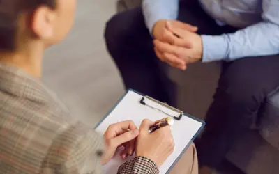 Sesja terapeutyczna, gdzie psychoterapeuta notuje ważne informacje. To obraz postępu w kierunku regulacji zawodu, jak ustawa o zawodzie psychoterapeuty.