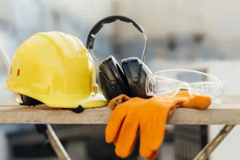 Żółty kask, słuchawki, okulary i rękawice. Podstawa bezpieczeństwa i higieny pracy na budowie.