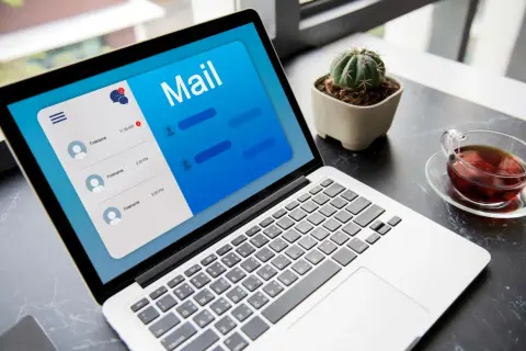 Laptop z otwartą aplikacją poczty, pokazującą jak napisać maila z CV. Obok filiżanka herbaty i mały kaktus.