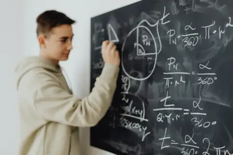 Chłopak pisze wzory matematyczne na tablicy. Czy to przedmioty, jakie odchodzą w 4 klasie liceum?