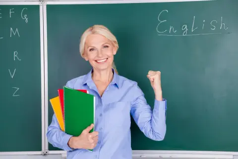 Uśmiechnięta nauczycielka z zeszytami, zaciśnięta pięść symbolizuje sukces w nauczaniu. Jej pensum nauczyciela jest pełne wyzwań, ale i satysfakcji.