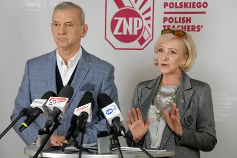 Dwoje przedstawicieli ZNP, związku zawodowego nauczycieli, podczas konferencji prasowej. Mężczyzna w kratę, kobieta w szarym żakiecie.