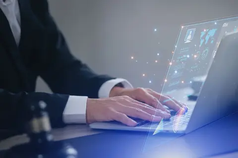 Prawnik w garniturze pracuje na laptopie, na ekranie wyświetla się interfejs z danymi i wykresami, symbolizującymi jego kluczowe kompetencje w cyfrowym świecie.