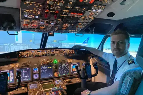 Młody pilot w kabinie samolotu, gotowy do lotu. Chcesz wiedzieć, jak zostać pilotem? To zdjęcie pokazuje początek tej fascynującej drogi.