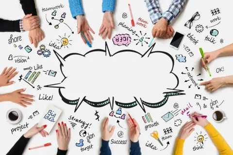 Ludzie tworzą burzę mózgów, rysując na stole słowa: teamwork, idea, plan, vision, share, think, talk, growth, success.
