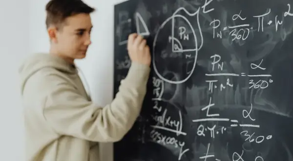 Chłopak pisze wzory matematyczne na tablicy. Czy to przedmioty, jakie odchodzą w 4 klasie liceum?
