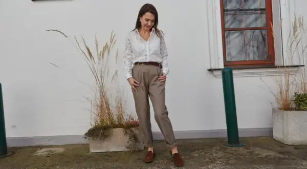 Elegancka stylizacja, która podpowie, jak się ubrać na rozmowę o pracę: biała koszula z ażurowymi detalami, brązowe spodnie i mokasyny.
