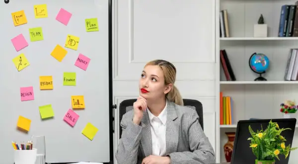 Kobieta w biurze z tablicą pełną karteczek samoprzylepnych z hasłami marketingowymi.