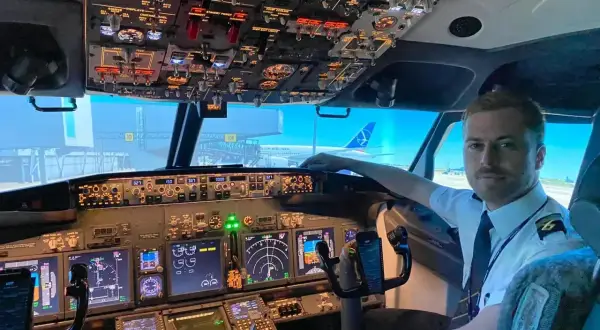 Młody pilot w kabinie samolotu, gotowy do lotu. Chcesz wiedzieć, jak zostać pilotem? To zdjęcie pokazuje początek tej fascynującej drogi.