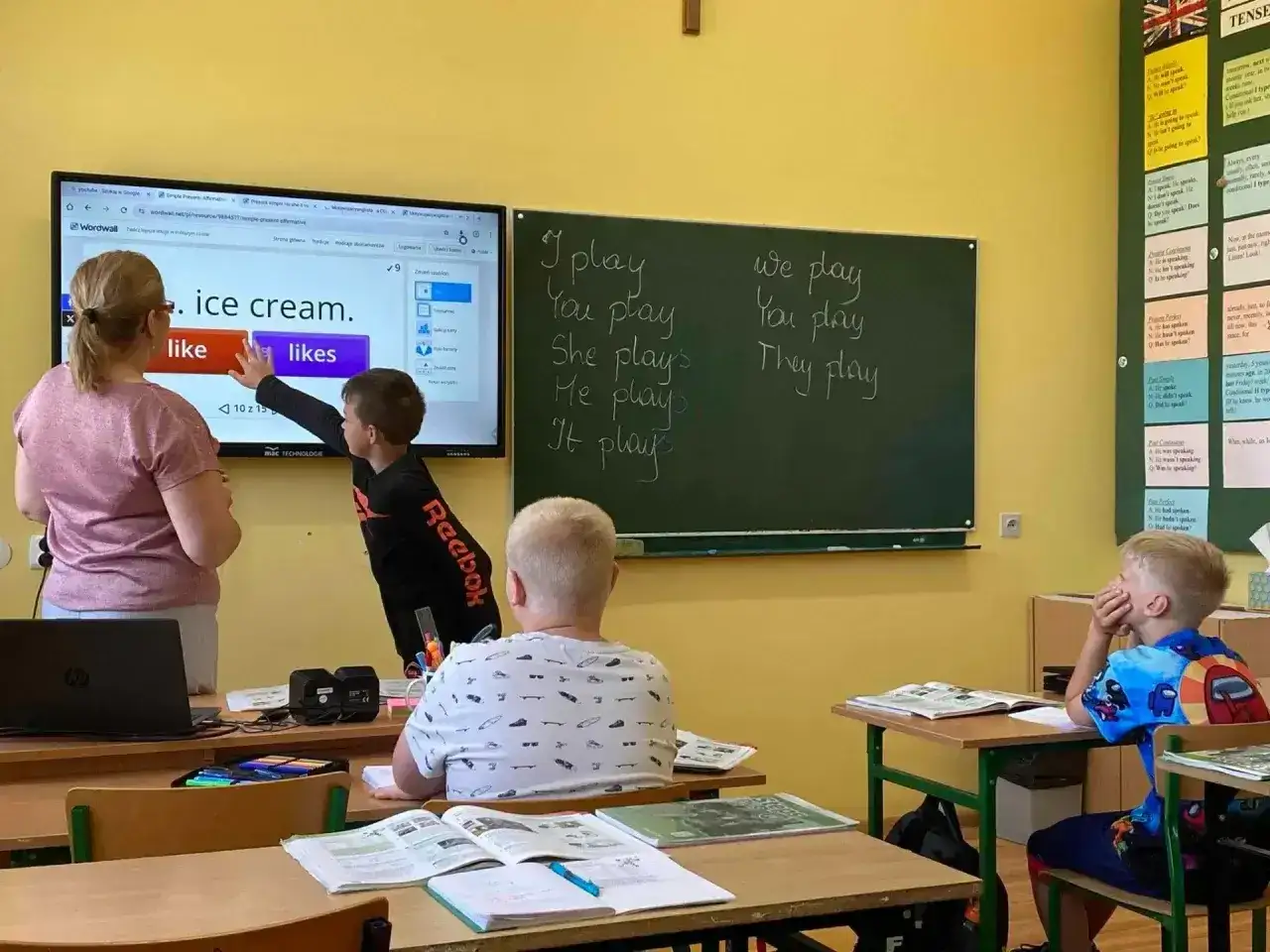 Nauczycielka z dzieckiem przy tablicy interaktywnej, ćwiczą angielski. Ciekawe, ile zarabia nauczyciel klas 1-3 za taką lekcję.