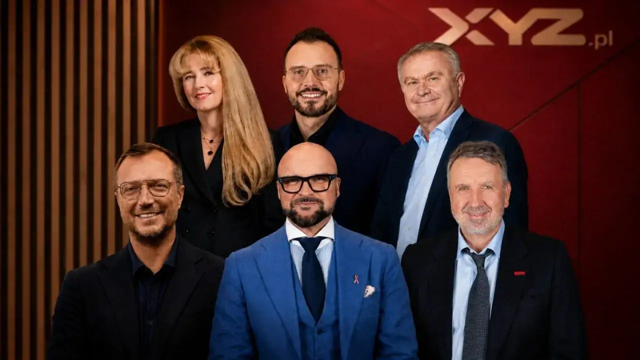 Grupa profesjonalistów, w tym mały przedsiębiorca, pozuje do zdjęcia. Wszyscy ubrani są elegancko, w garnitury i marynarki.