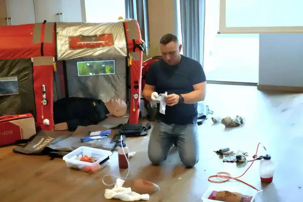 Ćwiczenia praktyczne podczas kpp kurs. Instruktor przygotowuje sprzęt medyczny obok manekina.