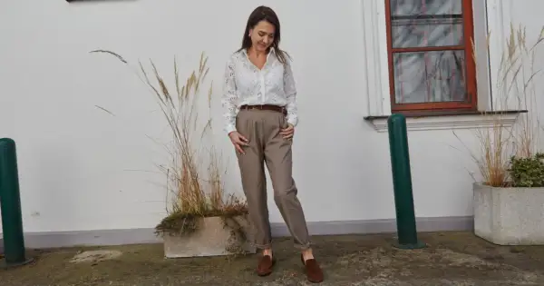 Elegancka stylizacja, która podpowie, jak się ubrać na rozmowę o pracę: biała koszula z ażurowymi detalami, brązowe spodnie i mokasyny.