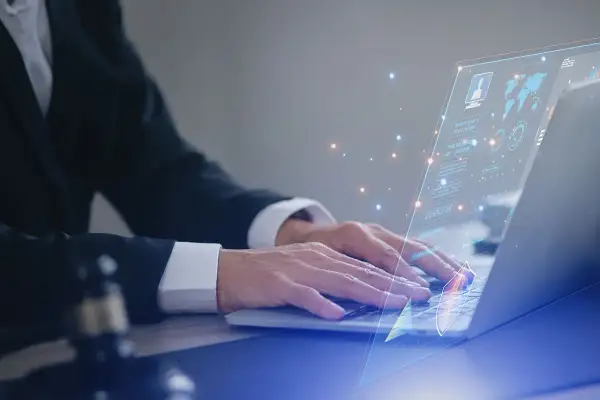 Prawnik w garniturze pracuje na laptopie, na ekranie wyświetla się interfejs z danymi i wykresami, symbolizującymi jego kluczowe kompetencje w cyfrowym świecie.